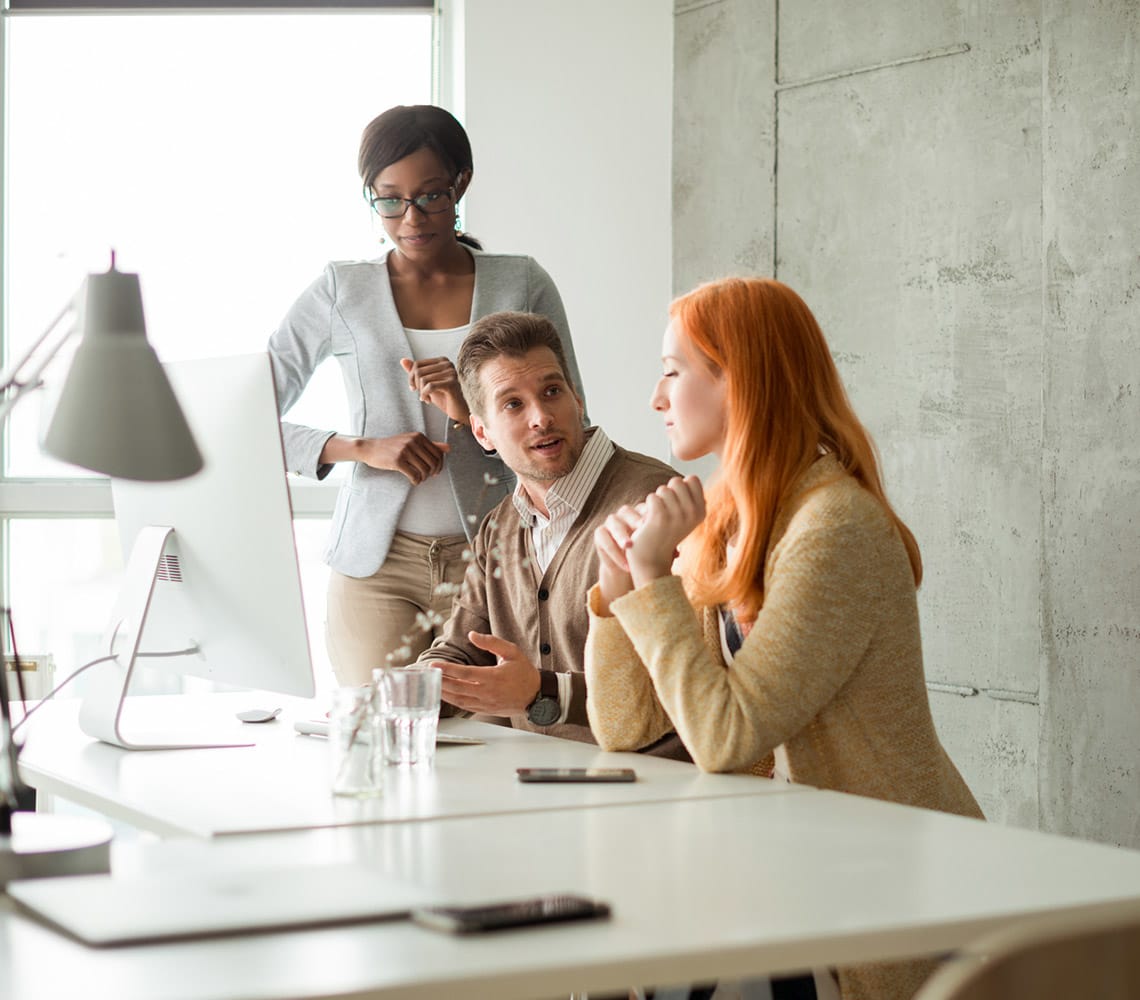 A group of people sitting at a table in an office having a discussion.